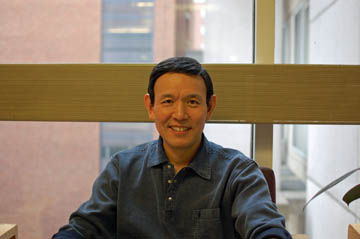 photograph of Jian Li sitting in chair in front of window