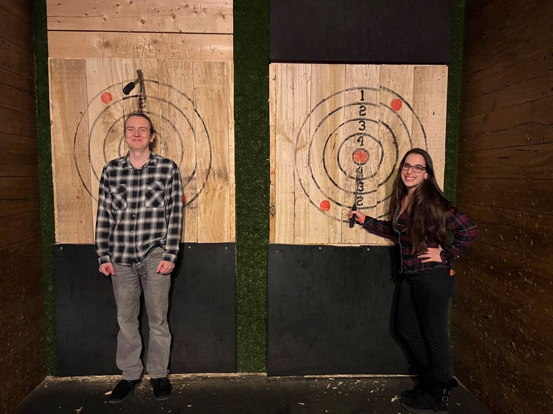 Two lab members pose in front of axe throwing bulls eyes