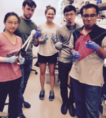 Five lab members standing in the lab with various laboratory instruments