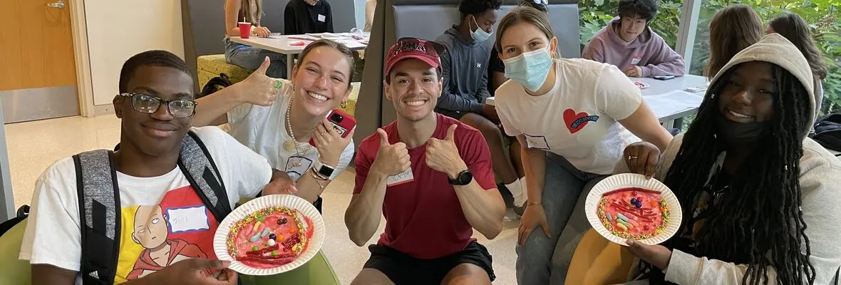 Five students smiling and displaying cell models made out of candy on paper plates