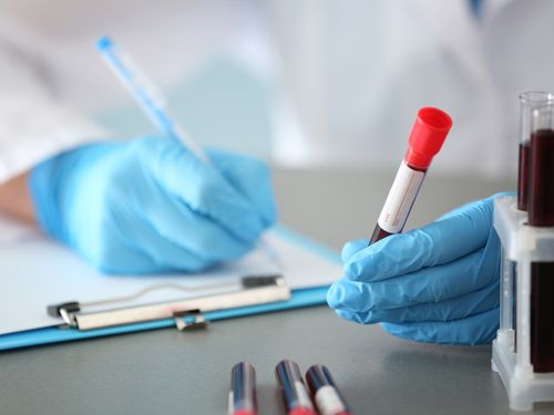 Woman working with blood sample in test tube at table