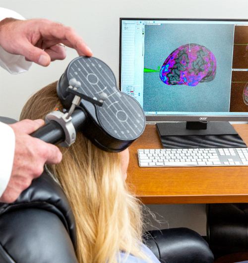 photo of device being operated and image of brain on computer screen