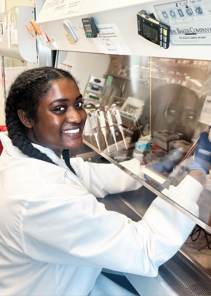 woman sitting at a hood with a pipette