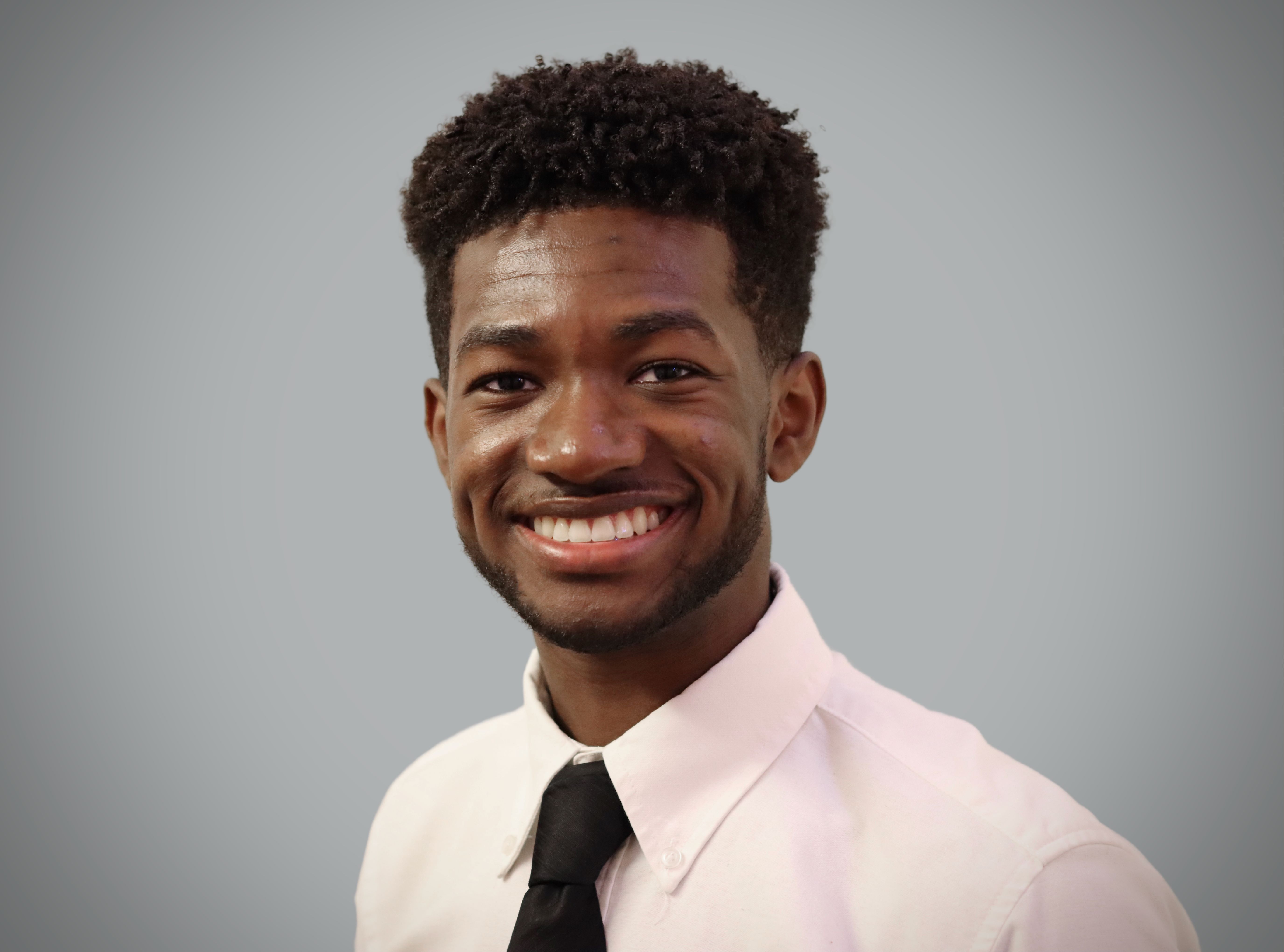 headshot photo of a man in front of a grey background