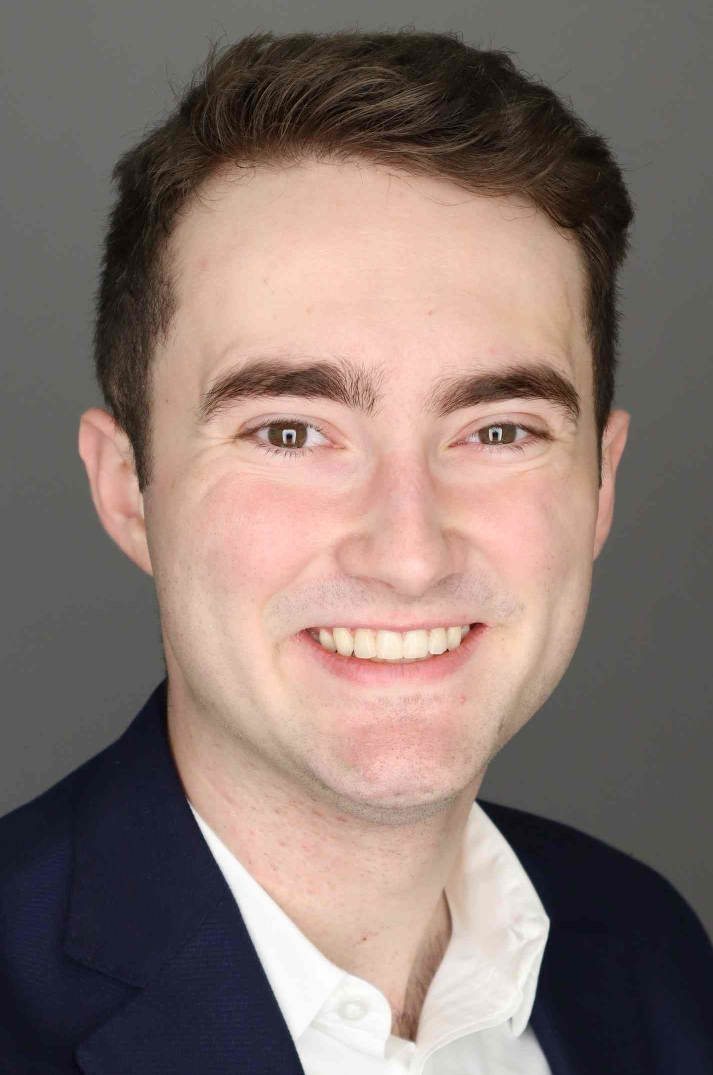 Photo of smiling man from shoulders up in white shirt and jacket