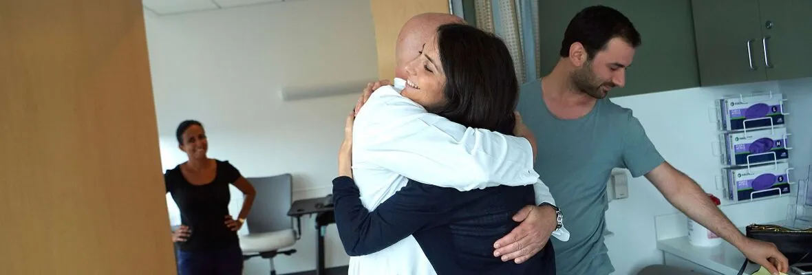 Doctor and patient hugging in exam room