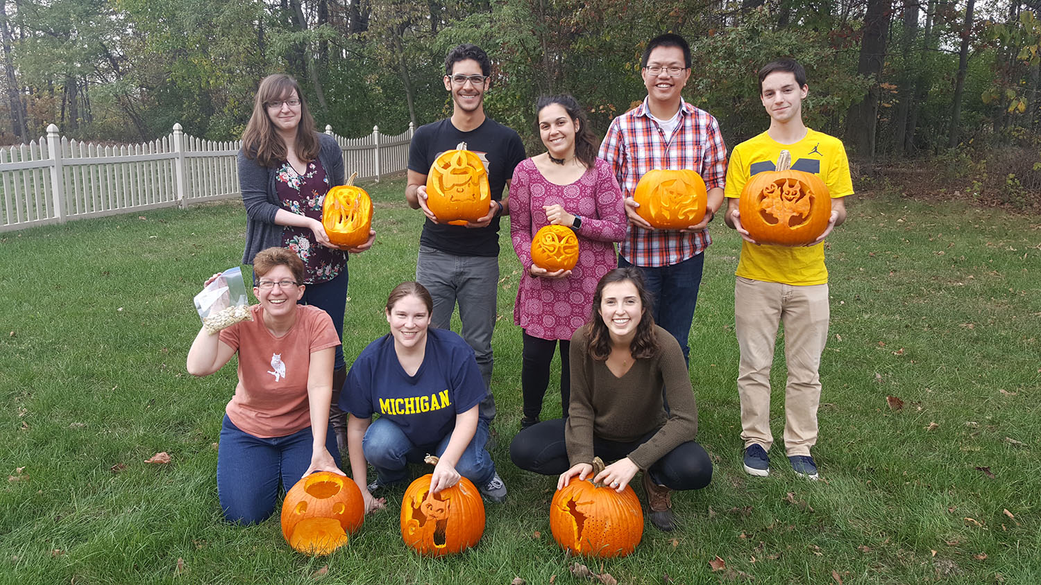 Group of lab members outside holding pumpkins that they have carved. 
