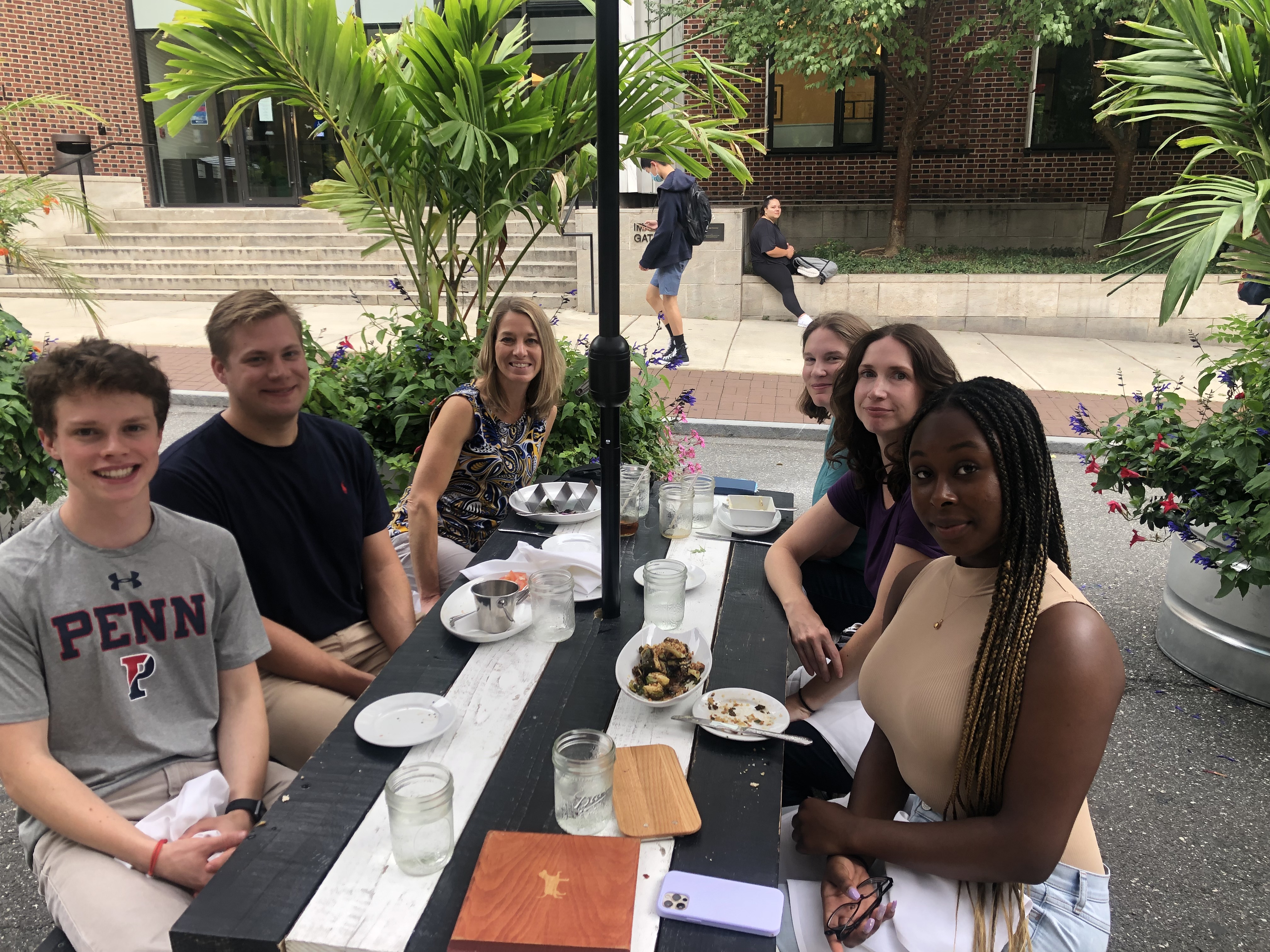 Photograph of six people sitting at a table outdoors.