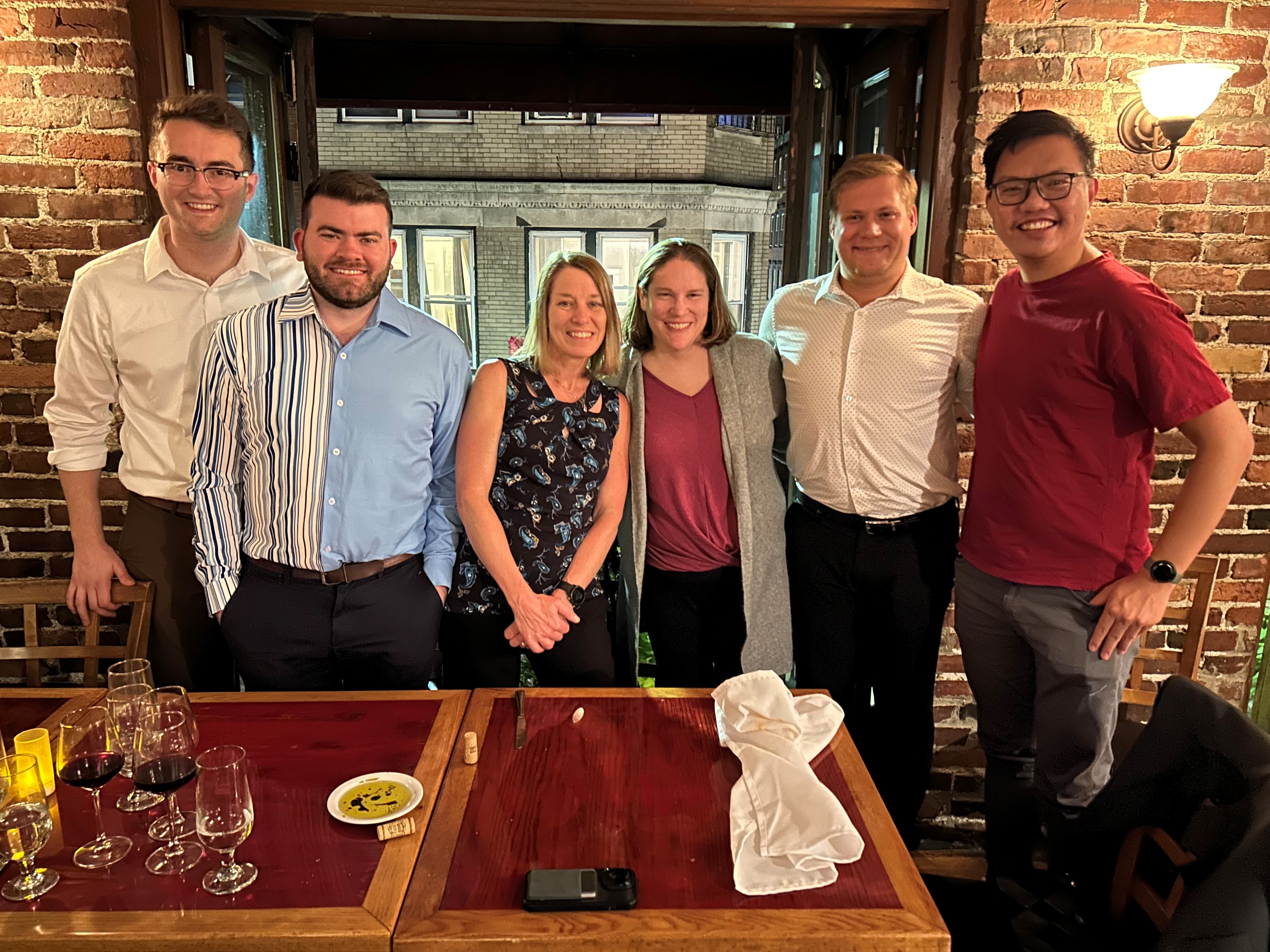 a group of 6 people standing behind a table at a restaurant