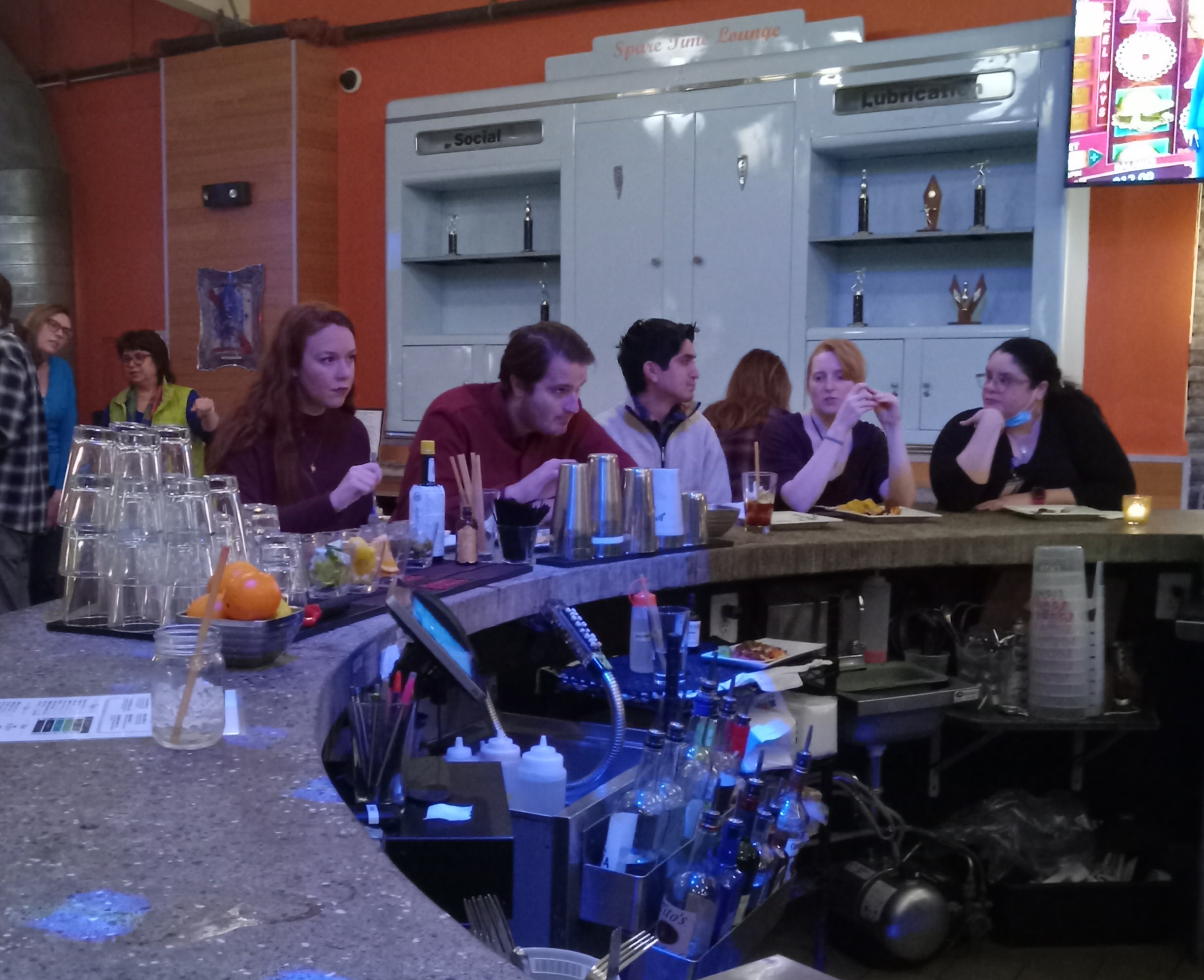Picture of some lab members sitting at the bowling alley bar, eating, drinking and talking