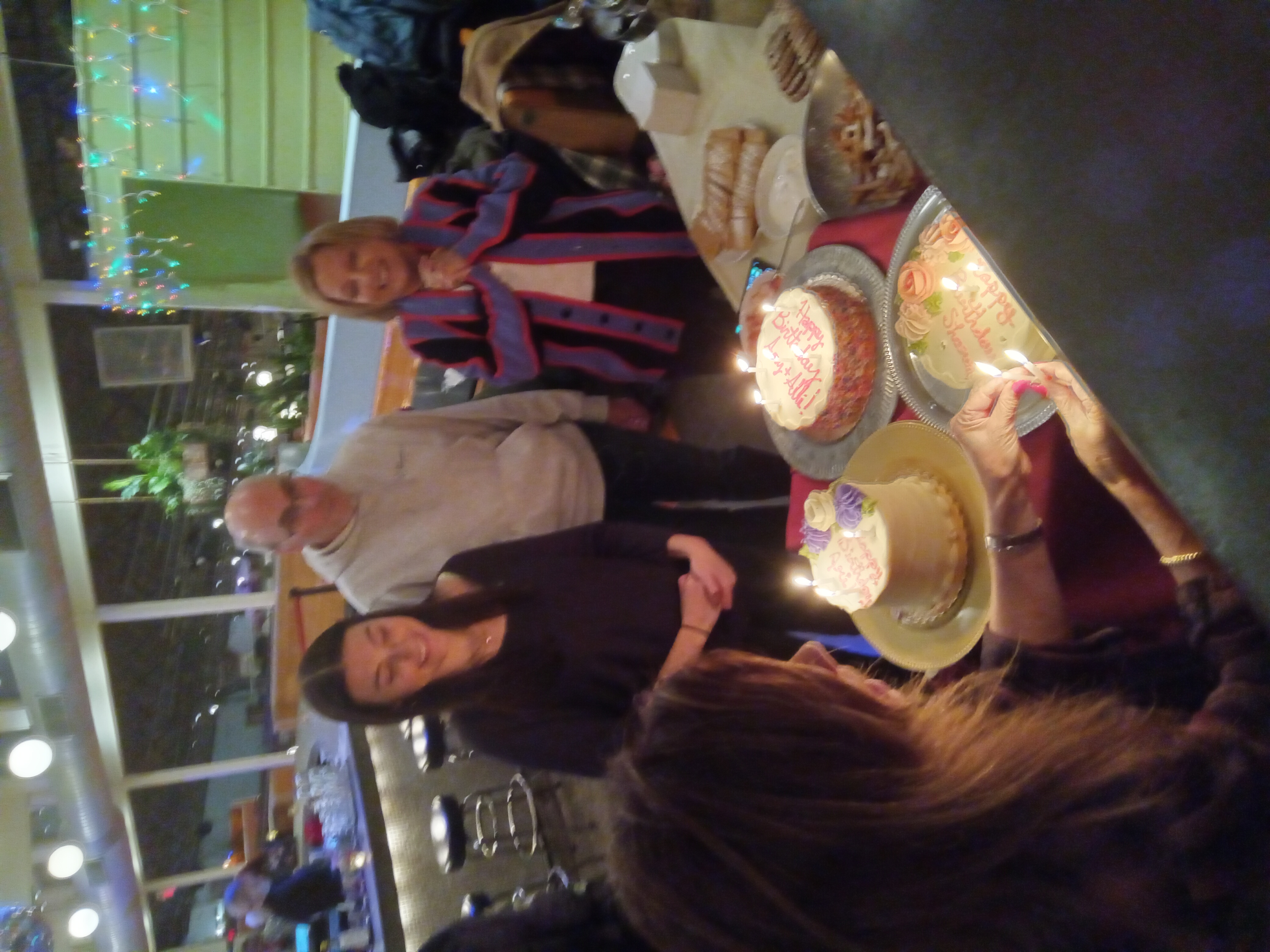 Drew Weissman with his wife and daughter, singing happy birthday while standing in front of a table with birthday cakes