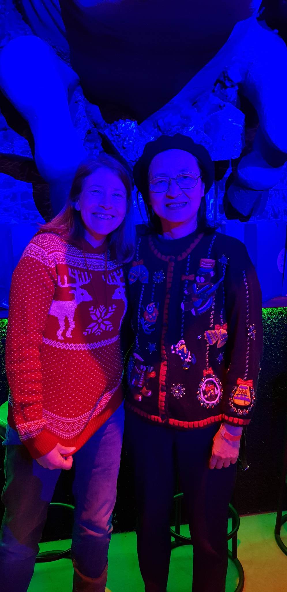 Two lab members smile for the camera while wearing holiday sweaters