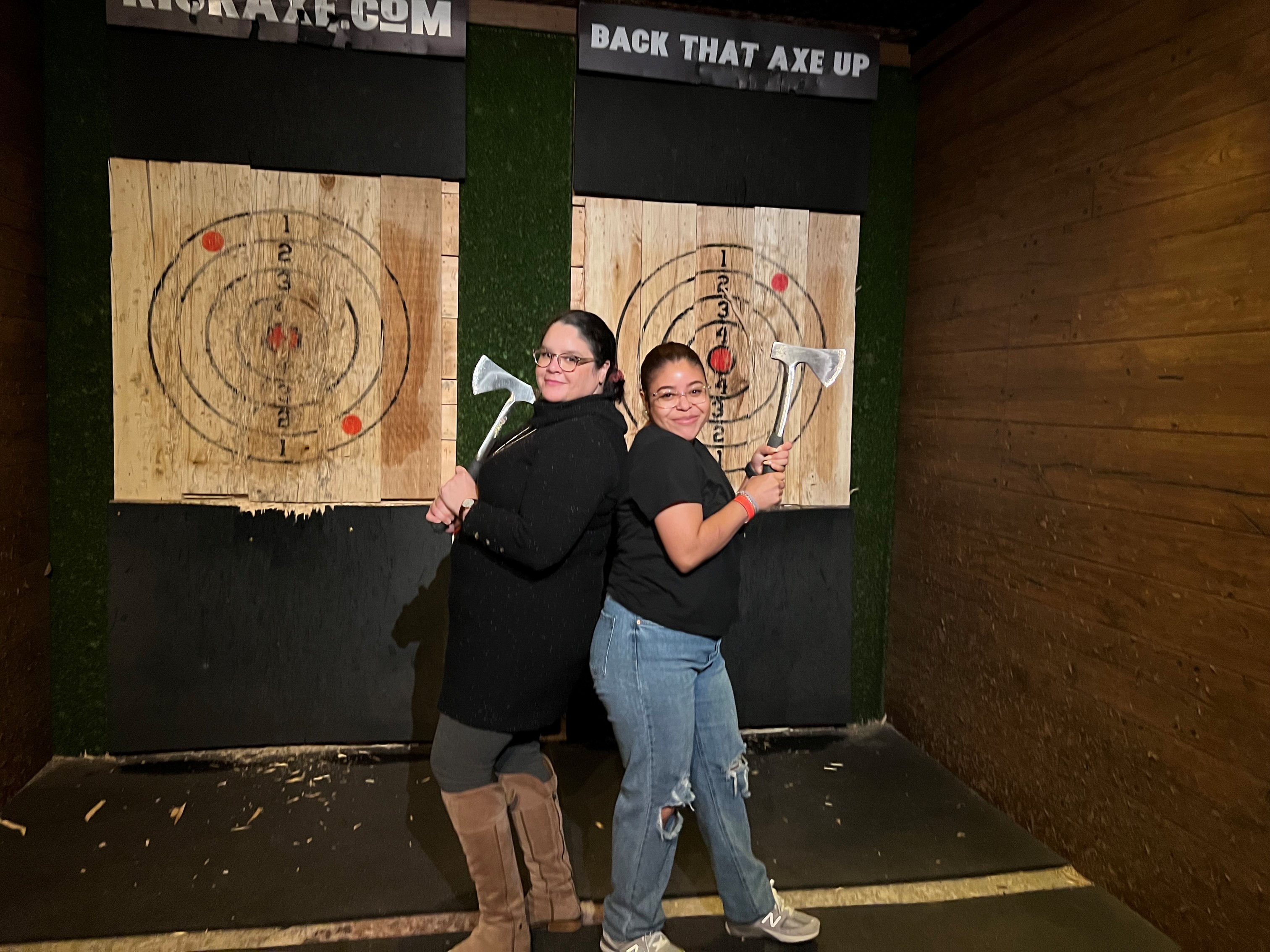 Two lab members pose while holding axes in front of the targets