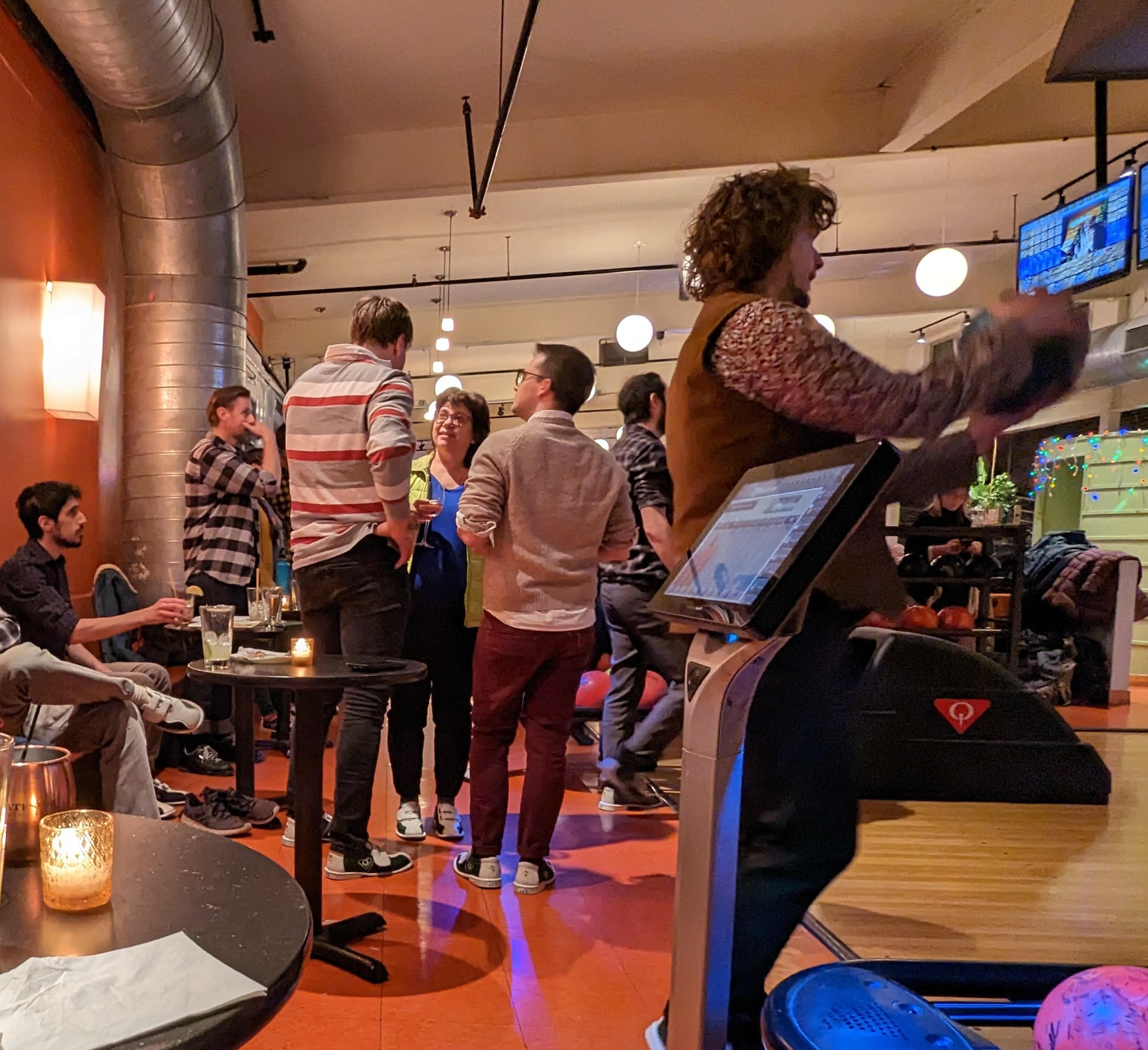 Picture of lab members standing in and beside bowling lanes, talking and picking bowling balls