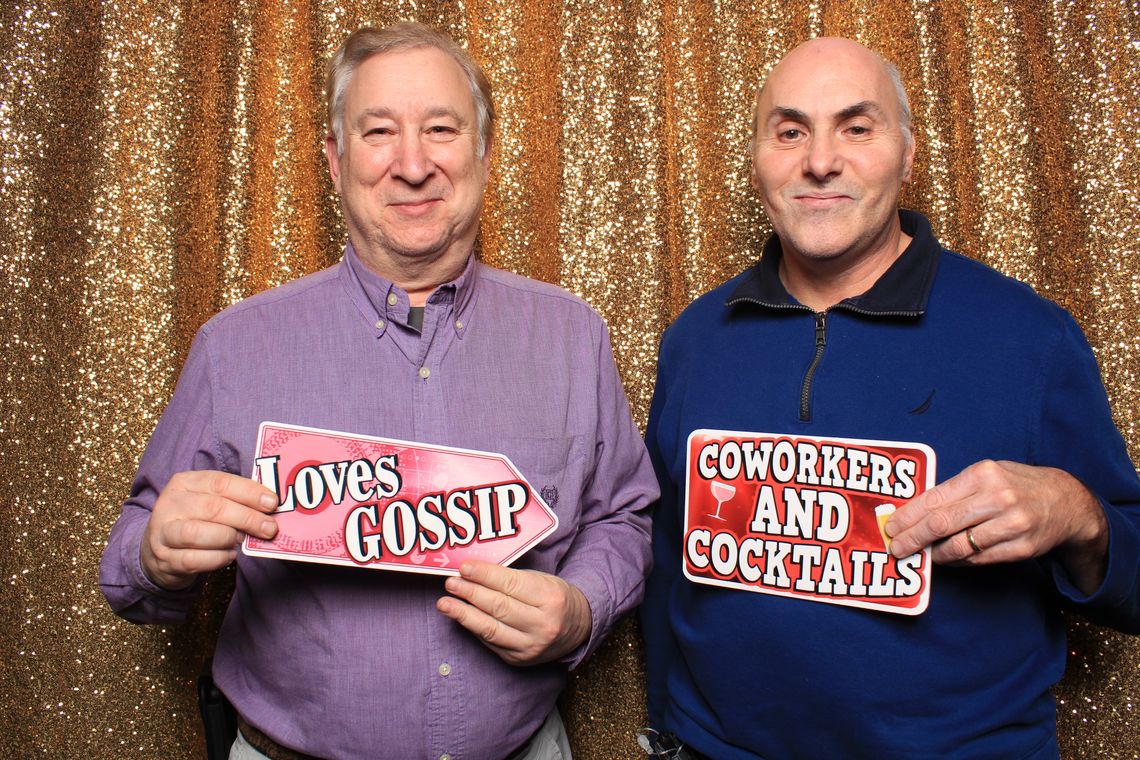 Two people smile and hold props in photo booth