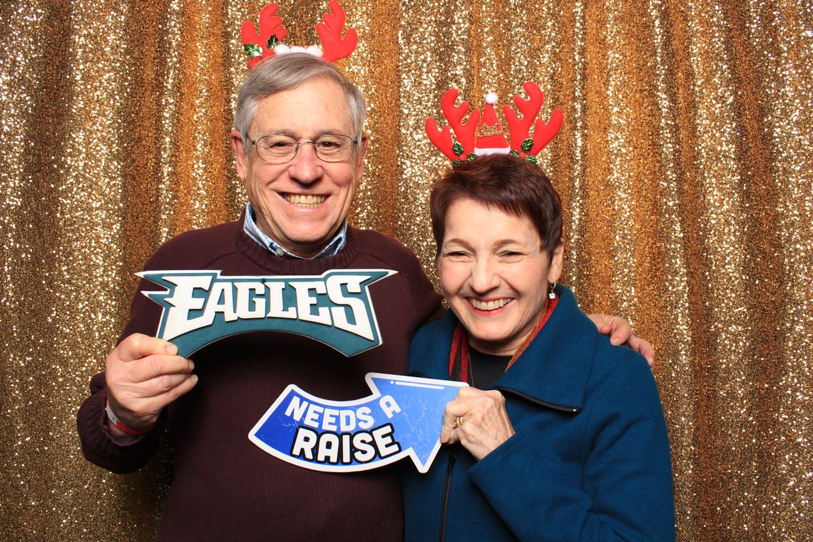 Two people smile and hold props in photo booth