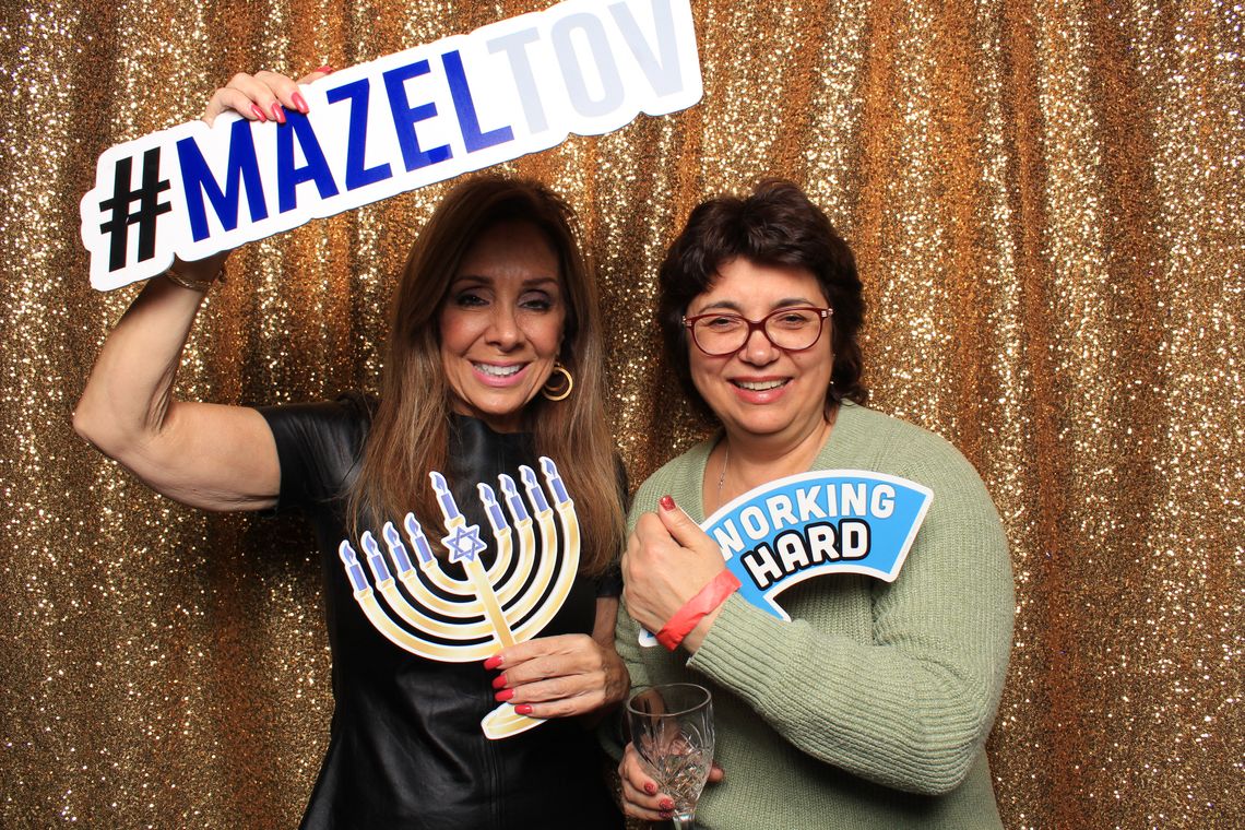 Two women smile and hold props in the photo booth