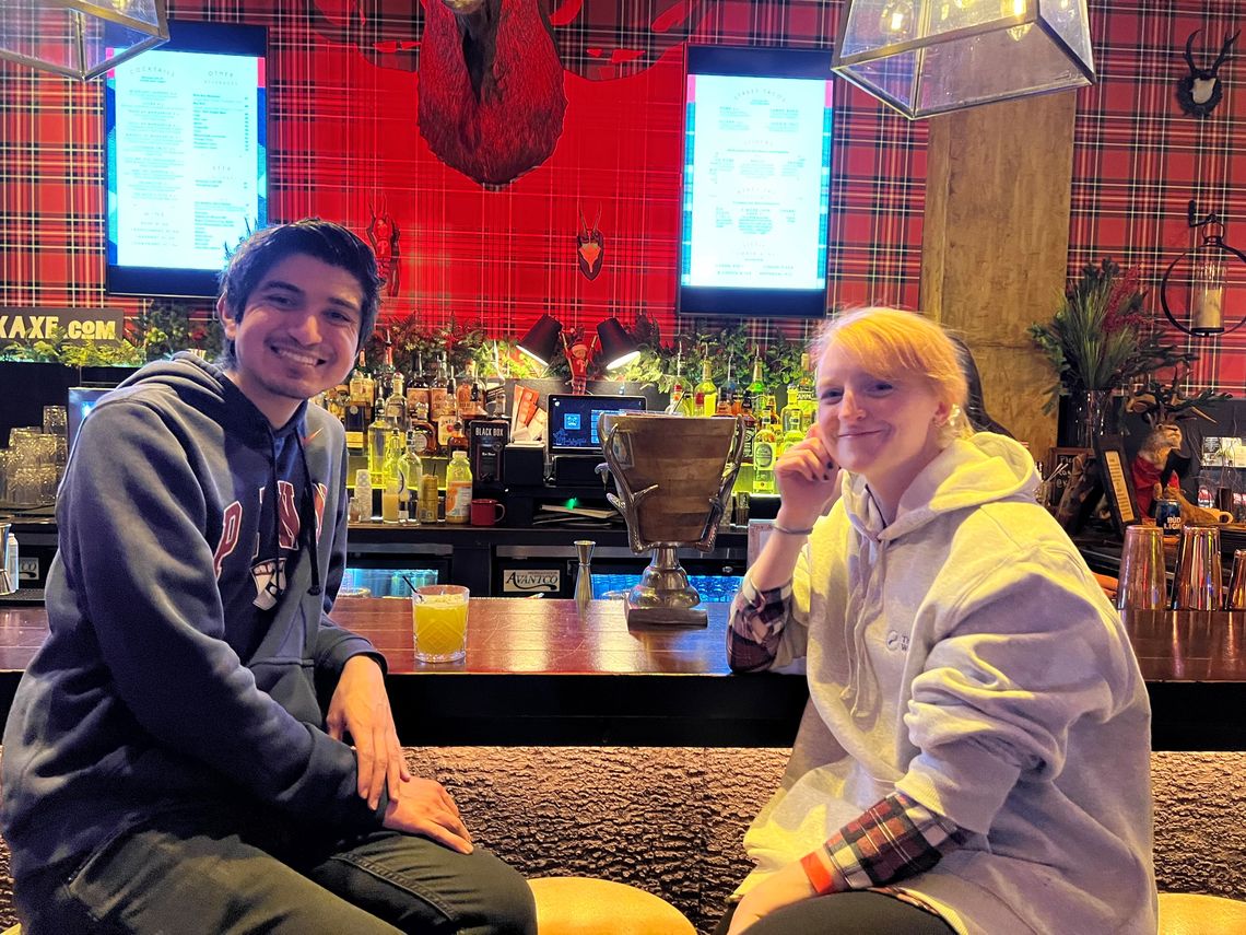 Two lab members sit at the bar and smile for the camera