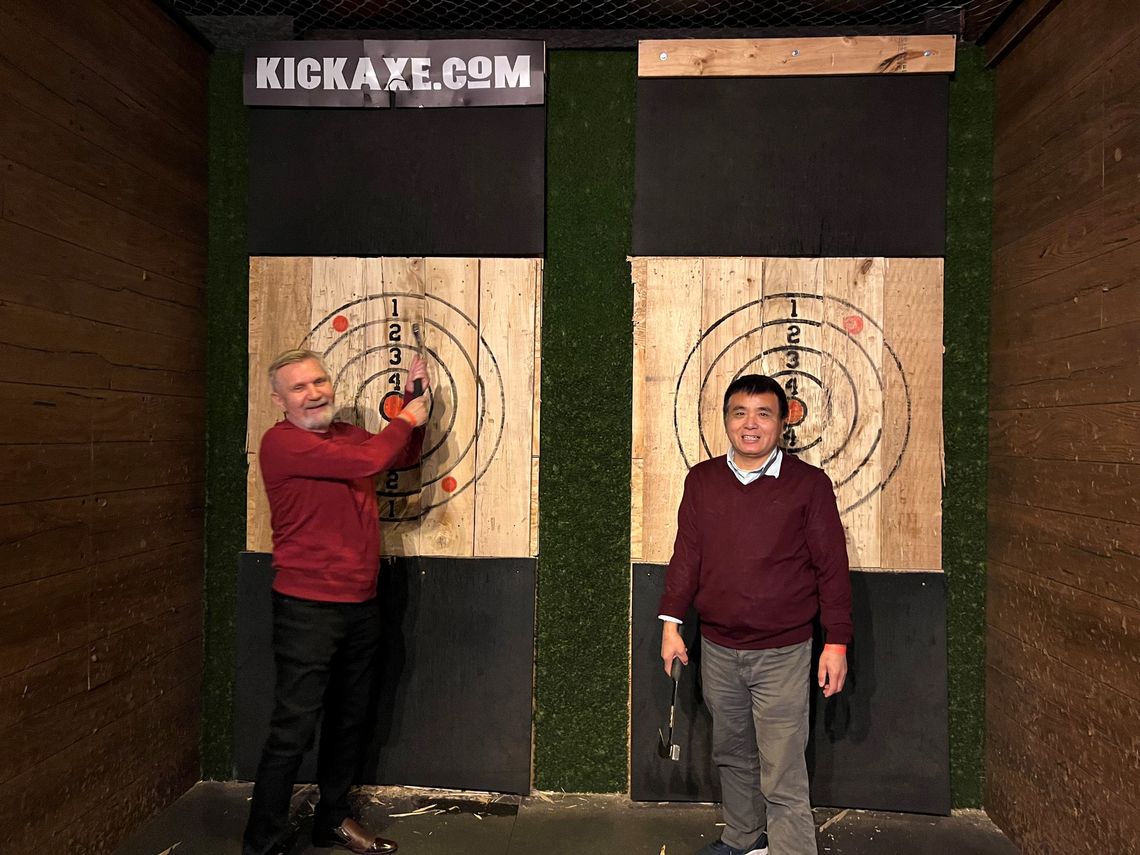 Two lab members laugh after throwing axes at bullseyes