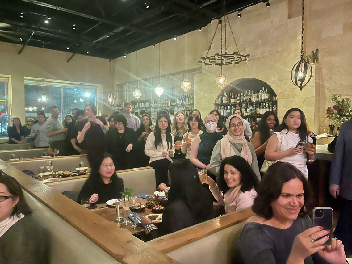 People standing and sitting, holding drinks and smiling