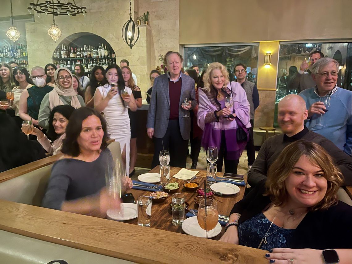 People standing and sitting at table, holding drinks